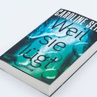 Buchcover mit Text: "Caroline Seibt - Weil sie lügt". Hintergrund in Blau- und Grüntönen. Genre: Thriller. Droemer Verlag.
