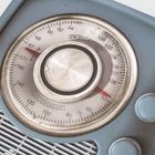 FM BROADCAST, AM BROADCAST. Ein blauer, vintage Radiotuner mit Skala und drei blauen Knöpfen.