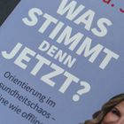 „Was stimmt denn jetzt?“ Groß in Weiß auf blauem Hintergrund. Darunter: Orientierung im Gesundheitschaos – online wie offline. Unten rechts ein lächelndes Gesicht.