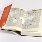 Maritimes Geld, 1694–1804. Eine Weltkarte zeigt das holländische Imperium. Aufgeklapptes Buch mit oranger Rückseite.