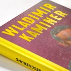 Auf einem gelben Buchrücken steht "LESUNG". Auf dem Cover steht "WLADIMIR KAMINER" in gelben Buchstaben. Ein Gesicht ist sichtbar.