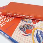 Zwei orange Bücher, eines mit dem Titel: "Wie ich gesund esse, ohne dabei komplett verrückt zu werden."