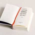 "Karsten Dusse, Achtsam morden am Rande der Welt, Roman. Ein aufgeschlagenes Buch mit rotem Leseband."