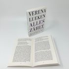 Text: "Verena Lueken Alles zählt Roman." Geschlossenes Buch aufrecht, davor ein aufgeschlagenes Buch, beide auf hellem Untergrund.
