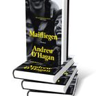 "Maifliegen" von Andrew O'Hagan. Ein aufgeschlagenes Buch liegt vor einem stehenden Buch mit schwarzem und gelbem Cover.