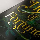 "Tide of Fortune" in goldener Schrift auf dunklem Hintergrund mit grünen Pflanzen und einem stilisierten Flügel.