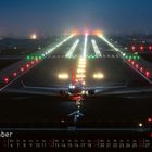 "Dezember" und "FLUG REVUE" unten, beleuchtete Landebahn im Nebel, Flugzeug startet, Lichter in Rot und Weiß.