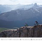 Kalenderblätter mit Monat Mai und Daten. Zwei Radfahrer fahren auf einem Bergpfad mit felsiger Landschaft.