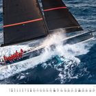 Eine große Segelyacht mit schwarzem Segel und roter Markierung gleitet dynamisch durch bewegte Wellen.