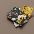 „UNTER GRUND“ in gelber Schrift. Ein Mann mit Hut auf Buchumschlag. Daneben gelbe Karte mit Gesichtern.