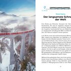 „Der langsamste Schnellzug der Welt“ steht oben. Ein roter Zug fährt über ein steinernes Viadukt in winterlicher Berglandschaft.