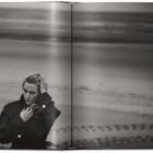 Das Bild zeigt eine Person am Strand, die nachdenklich in die Ferne schaut. Schwarz-Weiß-Aufnahme in einem Buch.