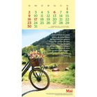 Kalender: Mai. Zitat: "Um wirklich zu leben, musst du heute leben." E-Bike mit Korb voller Blumen am See.