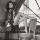 05. Eine Frau sitzt in einem stilvollen Raum auf einem Tisch neben einem Fenster, gekleidet in Spitzendessous.