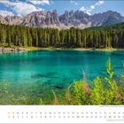 Text: "mai" und Tage des Monats in Kalenderdarstellung. Türkiser See, grüne Bäume, Berge, blauer Himmel.