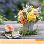 Text: "MAI". Kalender mit Röschen und Gänseblümchen in einer Tasse auf Holztisch dekoriert.