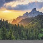 05 | MAI, Kalender mit Landschaft: Ein Sonnenuntergang über bewaldeten Bergen und Felsen, der Himmel ist mit Wolken bedeckt.
