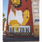 Eine große Wandmalerei zeigt eine stilisierte gelbe Hand über einem Klavier. Darunter steht "05" und "17".