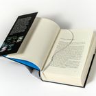 Links ein Blatt mit schwarzem Rand, darauf dichter Text und unten Bilder. Rechts ein aufgeschlagenes Buch mit Lesebändchen.