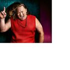 "Christoph Fiedler" unten links. Ein Mann im roten Pullunder, energiegeladene Pose mit Rock-Geste, vor buntem Hintergrund.