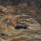 Ein weitläufiger Tagebau mit terrassenförmigen Abbauflächen und gewundenen Straßen in einer kargen Landschaft.