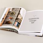 Text: "Teil Eins: Wohnen im Vintage-Stil". Ein aufgeschlagenes Buch zeigt ein Bild von einem stilvollen Regal.