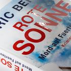 Text: "Eric Berg Rote Sonne: Mord auf Fuerteventura, Kriminalroman." Ein Buchcover mit wolkigem Himmelshintergrund.