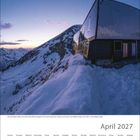 April 2027 Kalenderblatt, Bergkulisse bei Dämmerung, modernes Gebäude mit schneebedeckter Umgebung, warme Abendstimmung.