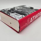ATWOOD, So etwas wie eine Erinnerung. Roter Buchrücken, Schwarzweiß-Fotografie einer Frau mit einem Buch.