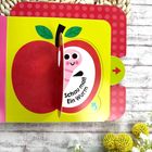 „Schau mal! Ein Wurm“ steht über einem runden Ausschnitt. Es zeigt einen lächelnden Wurm in einem roten Apfel.