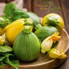 „Kochen ist wie Kino. Was zählt, ist das Gefühl.“ Anne-Sophie Pic. Verschiedene runde Zucchini auf Holzplatte. Mai-Kalender.