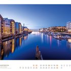 Text: "05 Hurtigruten, Hafen von Trondheim, Trøndelag, Norwegen." Abendansicht eines beleuchteten Hafens mit Booten und Gebäuden.