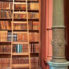 Das Leben gleicht öfter einem Roman als die Romane dem Leben. Bücherregal mit Leiter, kunstvoll verzierte Säule, Kalender.