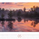 Kalender Mai 2023 mit Sonnenaufgangsszene am See, Bäume spiegeln sich im ruhigen Wasser, Himmel rosa-orange gefärbt.