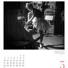 Mai-Kalenderblatt mit Zahl 5. Eine Ballerina bindet ihr Band, steht auf Spitze. Hintergrund Bühnenrequisiten.