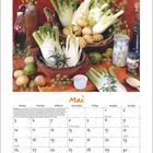 "Mai" steht groß über einem Kalender. Oben sind Fenchel, Kartoffeln und Küchenutensilien dekorativ arrangiert.
