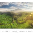 5. Eine grüne, terrassierte Landschaft mit Morgennebel, die von Sonne beleuchtet wird. Ein majestätischer Berg im Hintergrund.