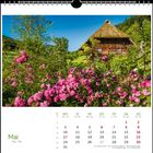 Mai. Monatskalender mit einem traditionellen Holzhaus und blühenden rosa Blumen im Vordergrund.