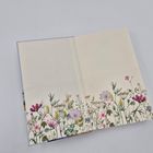 Zwei aufgeschlagene Seiten eines Buches mit floralen Illustrationen am unteren Rand in verschiedenen Farben.