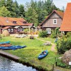 "Der Hafen von Leipe" ist am unteren Rand zu lesen. Ein ruhiger Wasserlauf mit blauen Kanus und traditionellen Häusern.