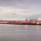 "HANSE UND HANDEL" steht im Text. Die Szene zeigt einen Hafen mit Kränen und Containern am Wasser bei Abenddämmerung.