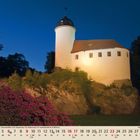 Text: "05" und Kalendertage unten. 

Abgebildet ist eine beleuchtete, mittelalterliche Burg auf einem Felsen bei Nacht.