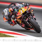 Kalender mit Mai und Renndaten. Ein Motorradfahrer in Schräglage auf einer Rennstrecke, trägt farbenfrohe Schutzkleidung.