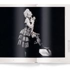 „French Bohème“, eine Frau singt in einem dekorativen Kleid, kniend auf einem Hocker mit elegantem Auftreten. 