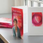 Buchtitel: "SEHNSUCHT nach LEBEN". Links zwei geschlossene Bücher, rechts ein offenes Buch mit einem abstrakten roten Bild.
