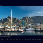 05 Mai. Südafrikanische Hafenstadt. Boote im Wasser, Gebäude im Hintergrund, beeindruckende Berge bei klarem Himmel.