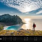 "05 Lofoten. Ryten, Moskenesøya. Wanderer blickt auf eine Bucht mit Bergen und Meer unter einem teils bewölkten Himmel."