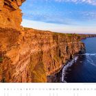 05, Die Cliffs of Moher im Licht der untergehenden Sonne. Steile Klippen, blaues Meer, klarer Himmel mit Wolken.