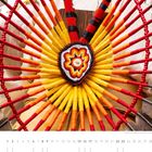Text: "Tradition und Rhythmus: Powwow im Wendake-Reservat der Huronen (Québec)." 
Farbenfrohes Indianerschmuck-Dekor.