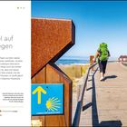 "Großes Ziel auf kleinen Wegen", beschreibt den Camino Português entlang der Westküste. Drei Personen wandern mit Rucksäcken.